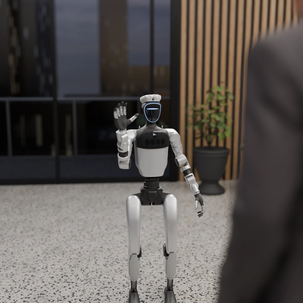 In an office lobby, the robot waves hello to an approaching guest
